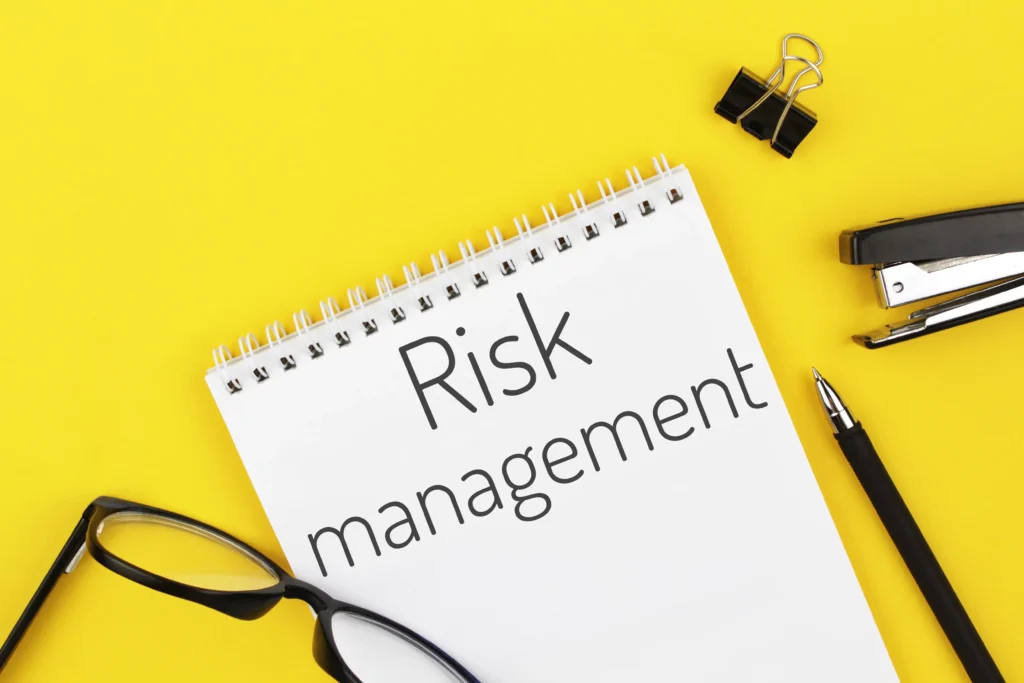 Risk management in forex signals concept with notebook, glasses, and office items on yellow background.