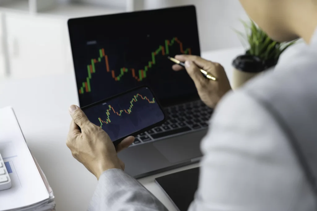 Trader analyzing Fibonacci Retracement Levels on laptop and smartphone charts