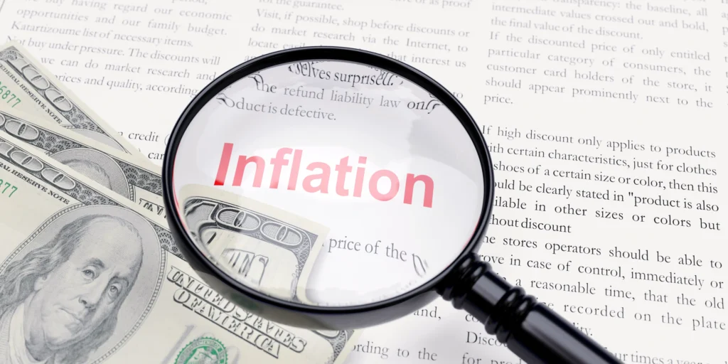 Magnifying glass showing the word inflation over US dollar bills, representing inflation and interest rates in forex markets 2025.