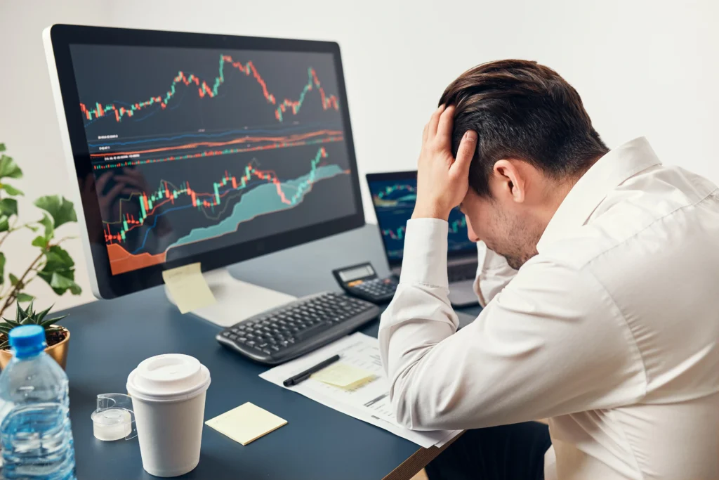 Frustrated forex trader watching multiple charts after overtrading losses