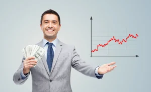 Smiling businessman holding dollar bills in one hand and gesturing toward a rising forex trading chart showing financial growth.