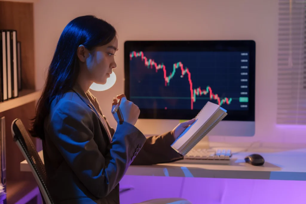Woman analyzing forex chart on computer while studying support and resistance strategy during market analysis.