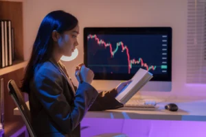 Woman analyzing forex chart on computer while studying support and resistance strategy during market analysis.