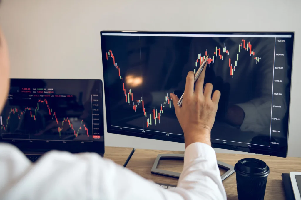 Trader analyzing forex candlestick chart on dual screens to identify pullback trading opportunities and trend continuation setups.