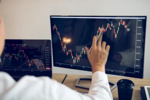 Trader analyzing forex candlestick chart on dual screens to identify pullback trading opportunities and trend continuation setups.
