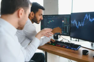 Two traders analyzing breakout vs fakeout signals on dual trading screens during low-volatility forex sessions.