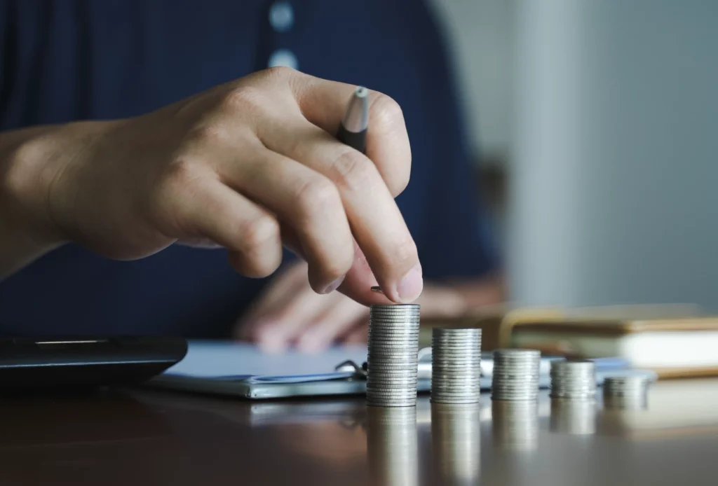 Person stacking coins on a table representing Average Return and investment growth.