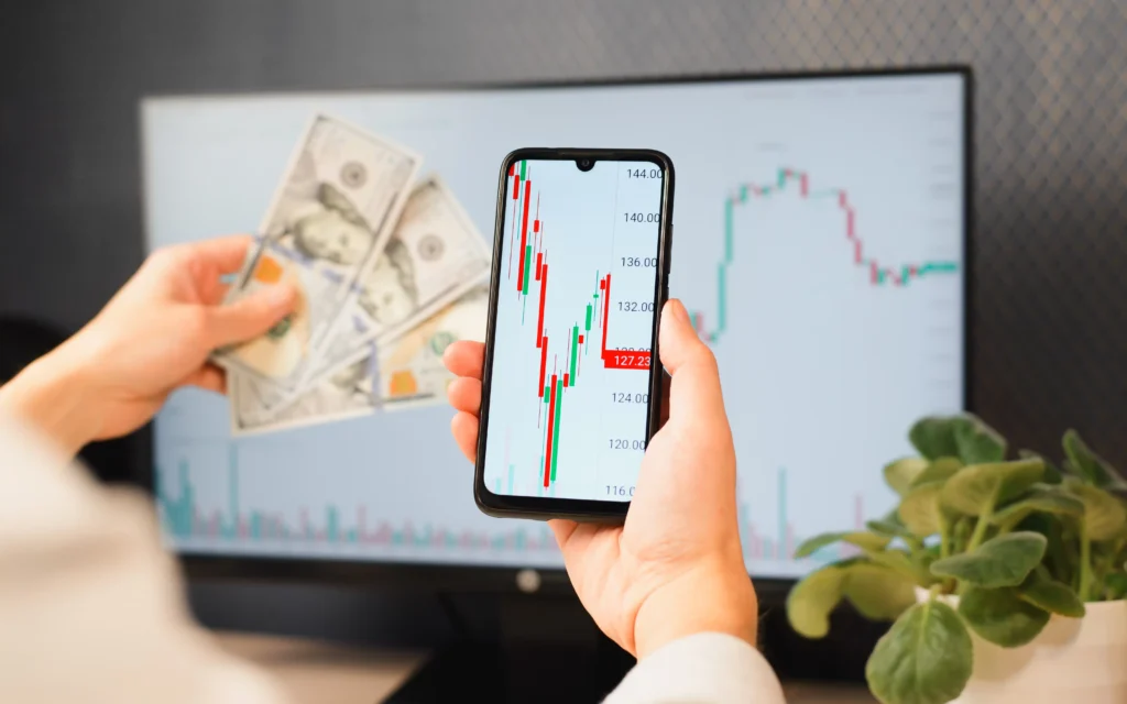 Trader analyzing live chart movements on phone with cash notes in hand representing Smart Money Concepts vs Classic Price Action.