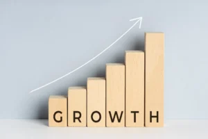 Wooden blocks forming a rising bar chart labeled growth with an upward arrow showing the concept of Compound Annual Growth Rate (CAGR).