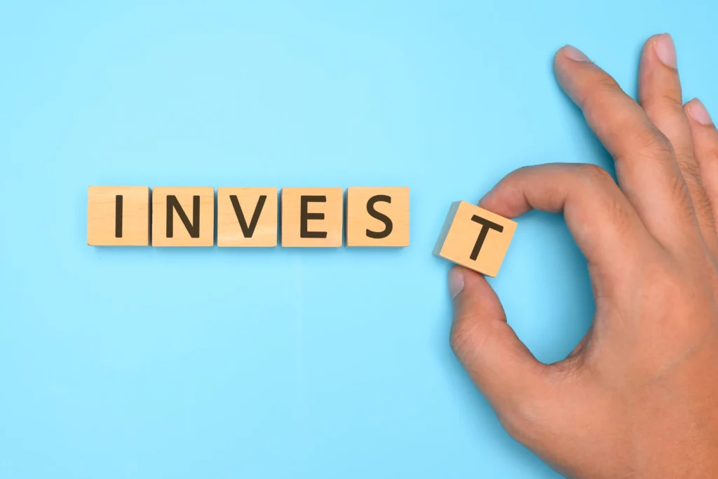 Active Investing in 2026 concept with wooden blocks spelling INVEST on blue background