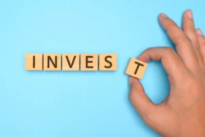 Active Investing in 2026 concept with wooden blocks spelling INVEST on blue background