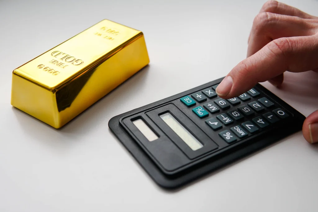 Gold bar beside a calculator representing Gold ETF investment decisions.