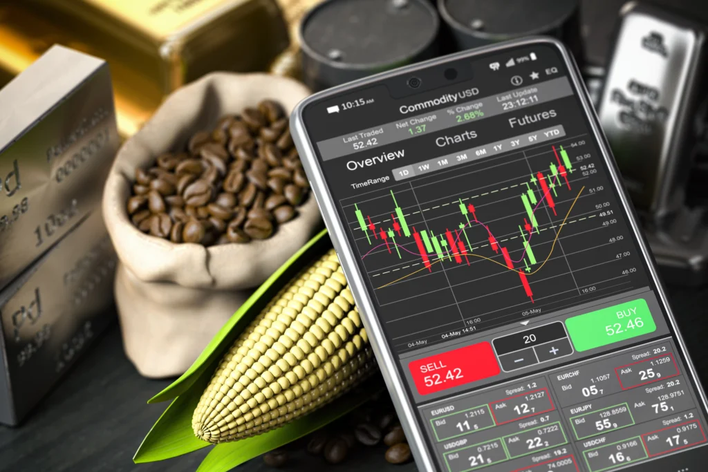 A smartphone displaying live commodity trading charts placed next to coffee beans, corn, and precious metal bars, symbolizing the rise of commodities beyond metals in global markets.