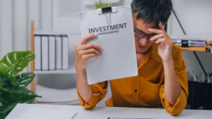 Investor stressed while reviewing poor portfolio performance, symbolizing the need to Sell a Losing Investment in 2026.