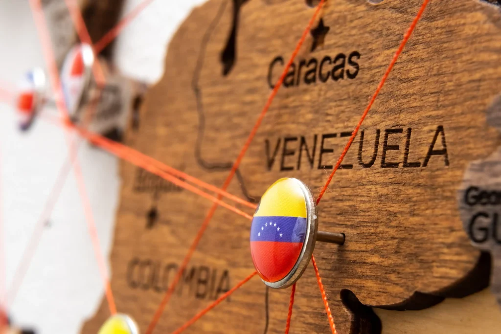 Map of Venezuela with a pin showing its flag connected by red trade lines representing U.S.–Venezuela 2026 relations.
